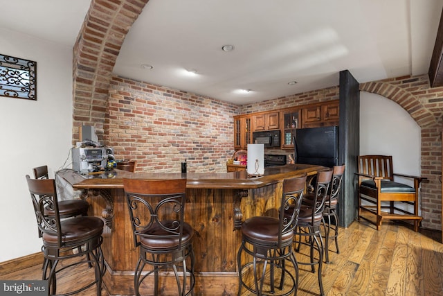 18309 Eldorado Way, Leesburg, VA 20176 - indoor wet bar with black appliances, light wood-style flooring, brick wall, and recessed lighting