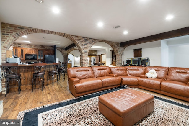 18309 Eldorado Way, Leesburg, VA 20176 - living room featuring arched walkways, ornate columns, brick wall, light wood finished floors, and bar area