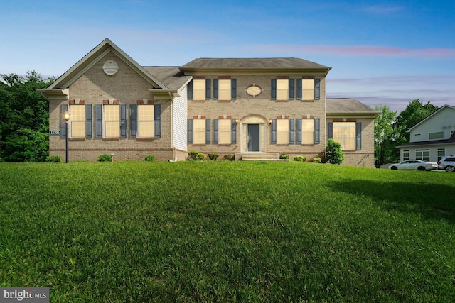 georgian-style home with a lawn and brick siding