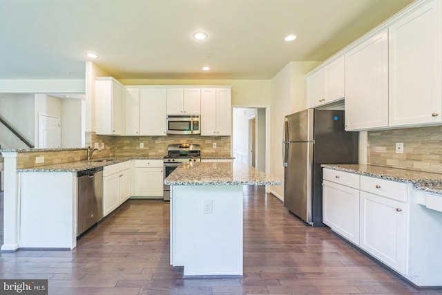 kitchen with appliances with stainless steel finishes, a sink, backsplash, white cabinetry, and recessed lighting