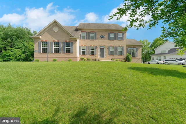 colonial house featuring a front yard and brick siding