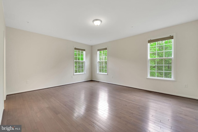 unfurnished room with baseboards and wood-type flooring