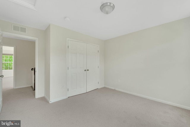 unfurnished bedroom featuring light carpet, a closet, and baseboards