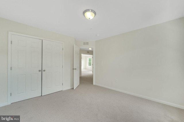 unfurnished bedroom featuring light colored carpet, baseboards, and a closet