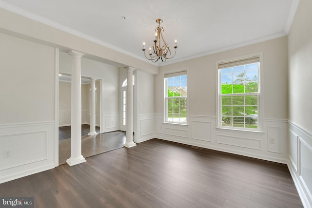 unfurnished bedroom with decorative columns, a wainscoted wall, dark wood-type flooring, a chandelier, and ornamental molding