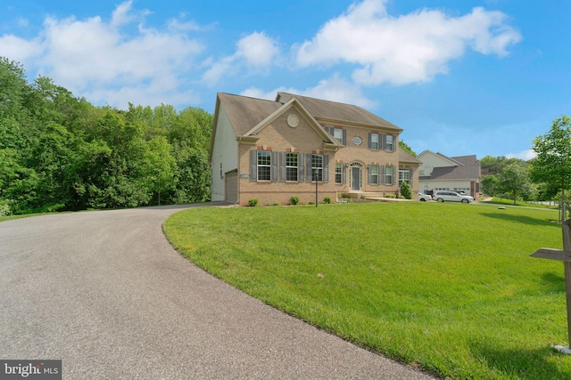 view of front facade with brick siding, asphalt driveway, a front lawn, and a garage