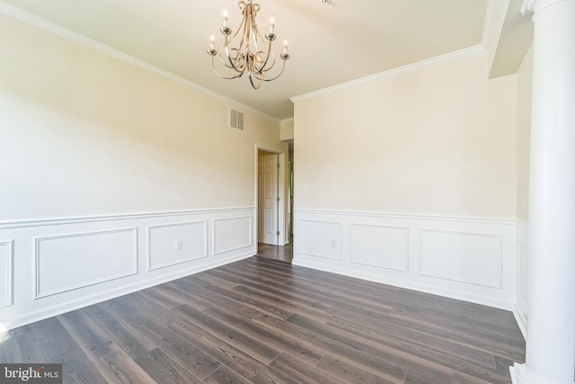 empty room with a chandelier, crown molding, dark wood-style floors, decorative columns, and a wainscoted wall