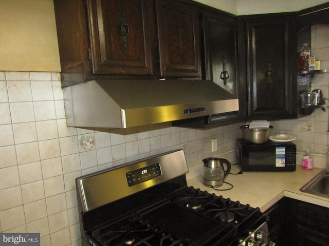 kitchen featuring gas stove, exhaust hood, light countertops, decorative backsplash, and dark brown cabinets