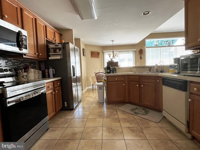 10127 Godspeed Dr, Ocean City, MD 21842 - kitchen featuring appliances with stainless steel finishes, a sink, tasteful backsplash, brown cabinets, and light countertops
