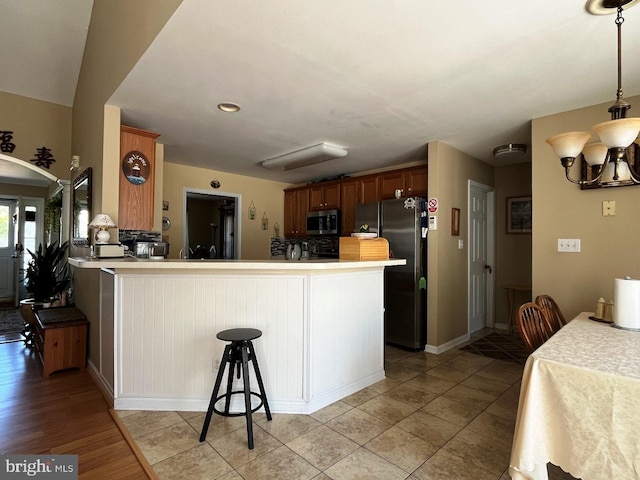 10127 Godspeed Dr, Ocean City, MD 21842 - kitchen featuring appliances with stainless steel finishes, a peninsula, a chandelier, light countertops, and decorative light fixtures
