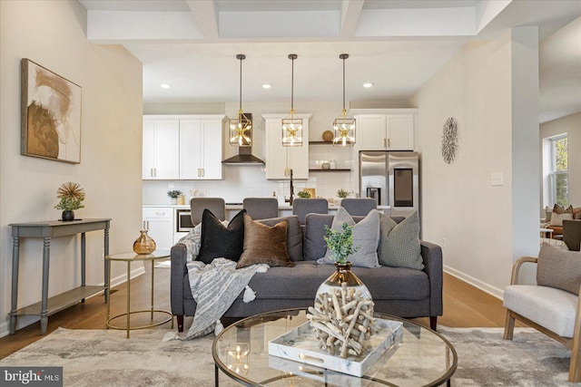 living area with light wood-type flooring, baseboards, recessed lighting, and beam ceiling