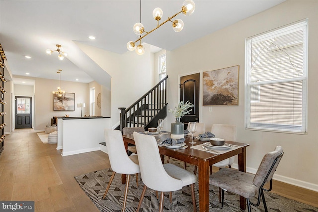 dining space with wood finished floors, healthy amount of natural light, a chandelier, stairs, and recessed lighting