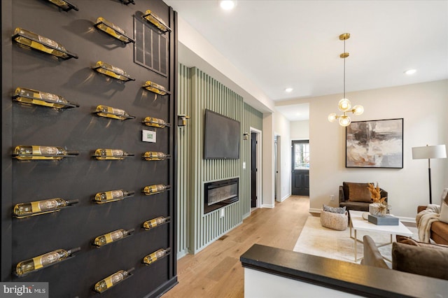 living room with light wood-style floors, baseboards, a glass covered fireplace, and recessed lighting
