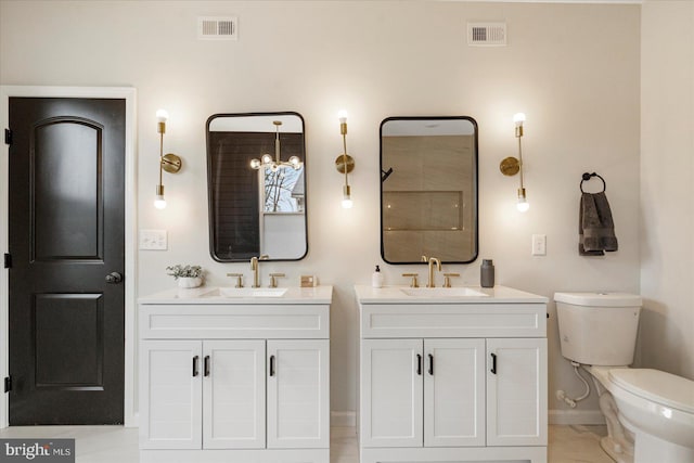 full bathroom with baseboards, two vanities, and toilet