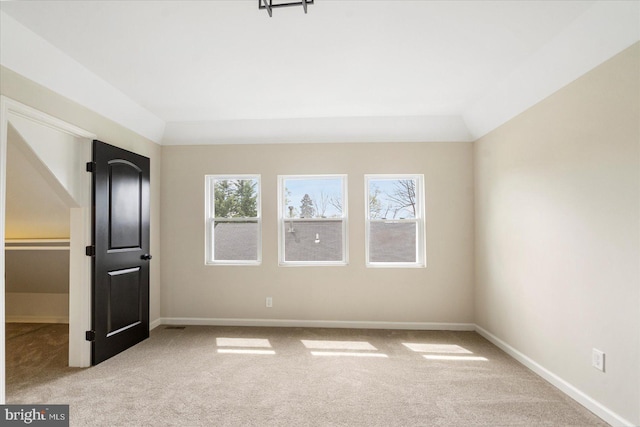 unfurnished bedroom with carpet flooring, multiple windows, baseboards, and vaulted ceiling