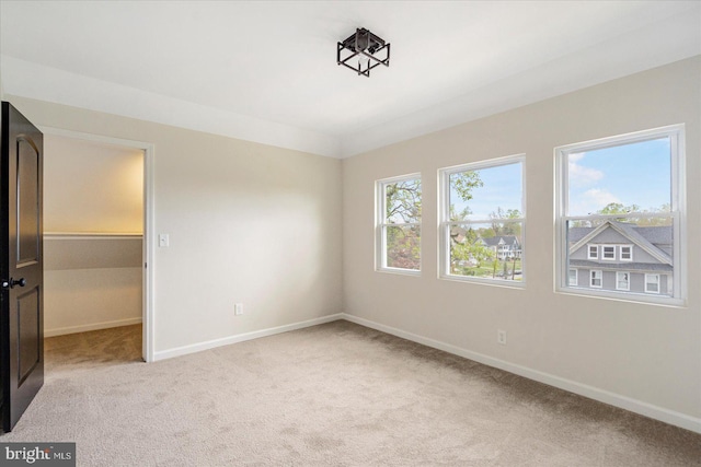 unfurnished bedroom featuring light colored carpet, baseboards, and a spacious closet