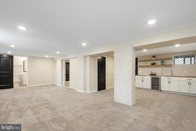 unfurnished living room featuring wine cooler, light colored carpet, wet bar, recessed lighting, and baseboards