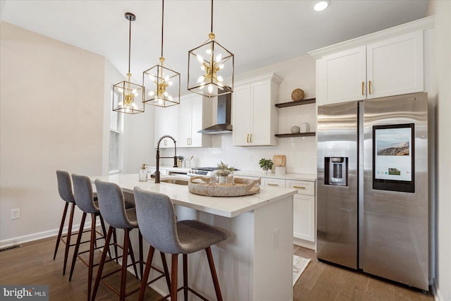 kitchen featuring stainless steel fridge, open shelves, a sink, wall chimney exhaust hood, and wood finished floors
