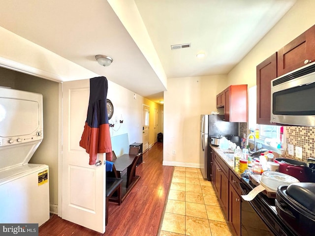 1431 N 17th St, Philadelphia, PA 19121 - kitchen featuring appliances with stainless steel finishes, stacked washer / dryer, a sink, tasteful backsplash, and light wood-type flooring