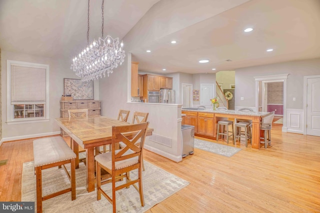 dining space featuring light wood-type flooring, a chandelier, vaulted ceiling, recessed lighting, and a wainscoted wall