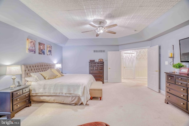 bedroom with light colored carpet, a ceiling fan, and a raised ceiling