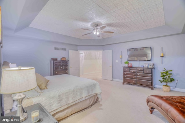 carpeted bedroom with a tray ceiling, baseboards, and a ceiling fan