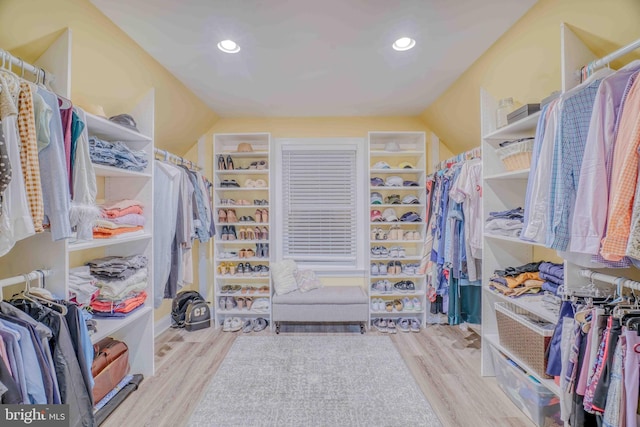 walk in closet with wood finished floors and vaulted ceiling