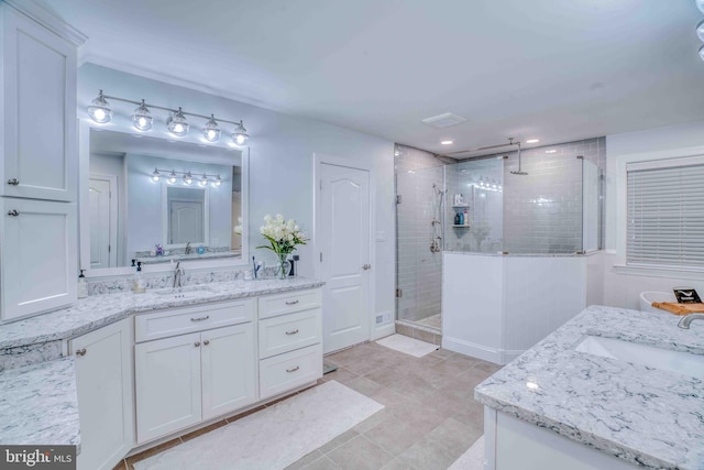 full bathroom featuring a stall shower, two vanities, and tile patterned flooring