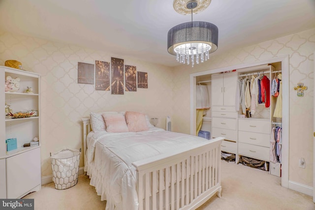 bedroom with a closet, light carpet, wallpapered walls, a chandelier, and baseboards