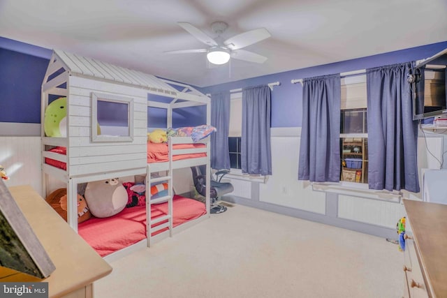 bedroom with carpet floors, a wainscoted wall, and ceiling fan
