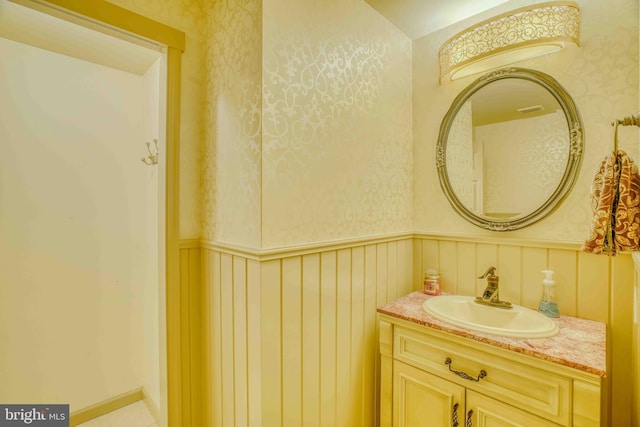 bathroom with wainscoting, wallpapered walls, and vanity