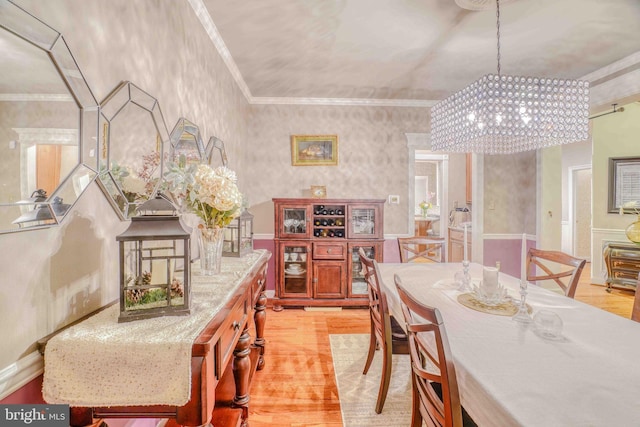 dining area with a chandelier, light wood-type flooring, and crown molding