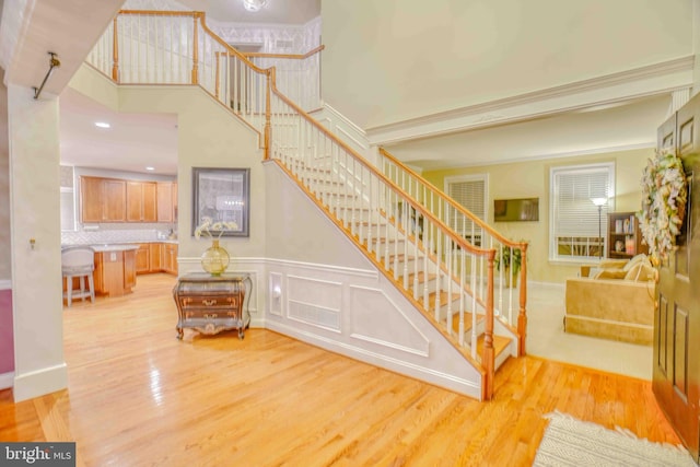stairway with wood finished floors and a wainscoted wall