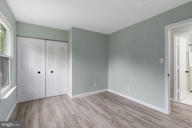 unfurnished bedroom with wood finished floors, baseboards, and a closet