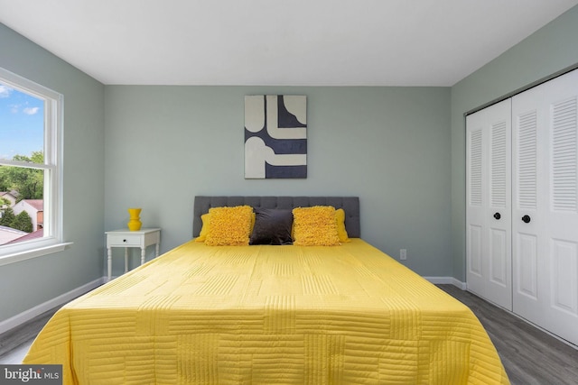 bedroom with dark wood-type flooring, a closet, and baseboards