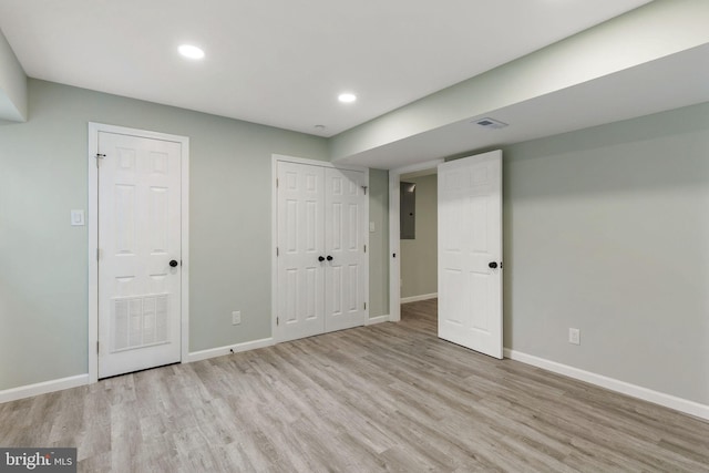 below grade area with wood finished floors, baseboards, recessed lighting, and electric panel