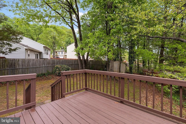 deck with a shed, a fenced backyard, and an outdoor structure