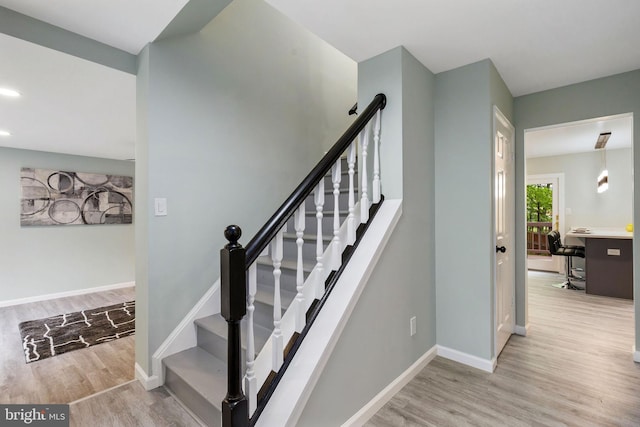 stairs featuring wood finished floors, baseboards, and recessed lighting