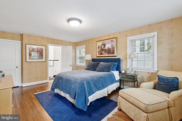 bedroom with wallpapered walls, wood finished floors, and baseboards