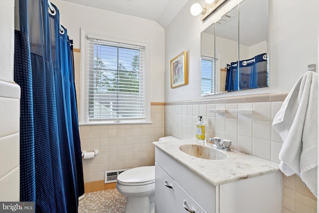 bathroom with tile walls, vanity, toilet, a wainscoted wall, and a shower with shower curtain