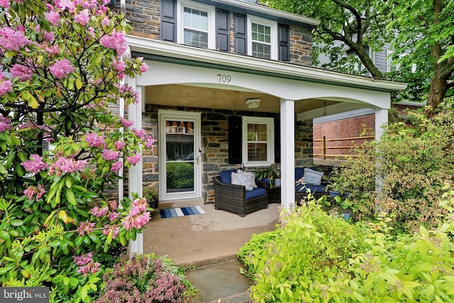 view of exterior entry with stone siding and covered porch