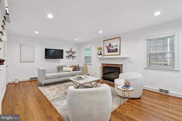 living area featuring a brick fireplace, wood finished floors, baseboards, and recessed lighting