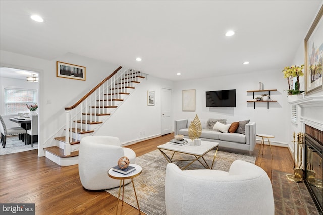 living area with wood finished floors, stairs, recessed lighting, a fireplace with flush hearth, and baseboards
