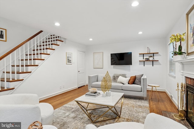 living room with wood finished floors, recessed lighting, a glass covered fireplace, stairs, and baseboards