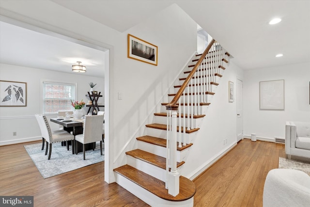 stairs featuring wood finished floors, baseboards, and recessed lighting