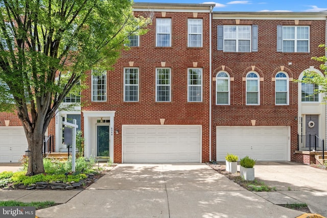 townhome / multi-family property featuring concrete driveway, brick siding, and a garage
