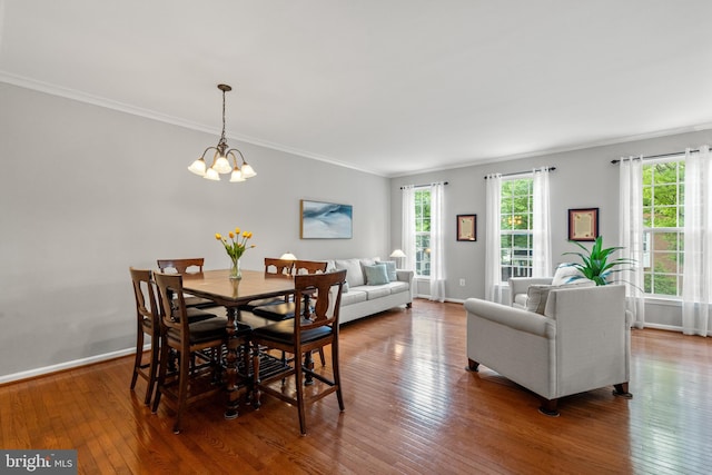 dining space with ornamental molding, hardwood / wood-style flooring, a chandelier, and baseboards