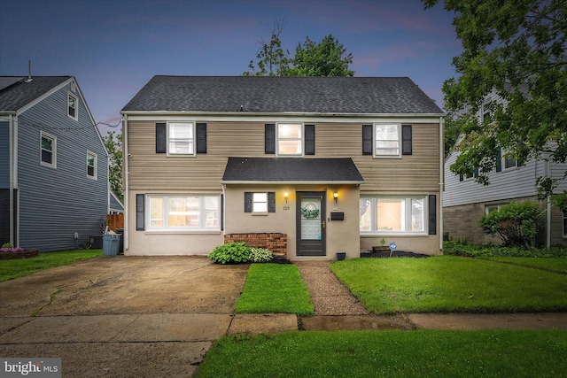 traditional-style home featuring a yard and roof with shingles
