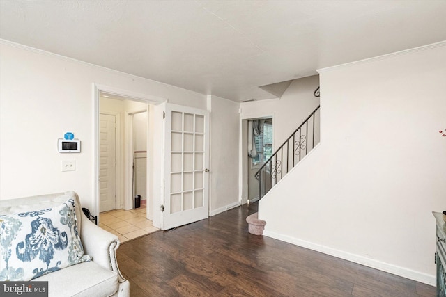 living area featuring wood finished floors, stairway, crown molding, and baseboards
