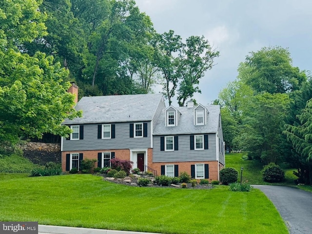 tri-level home with a front yard, brick siding, and a chimney